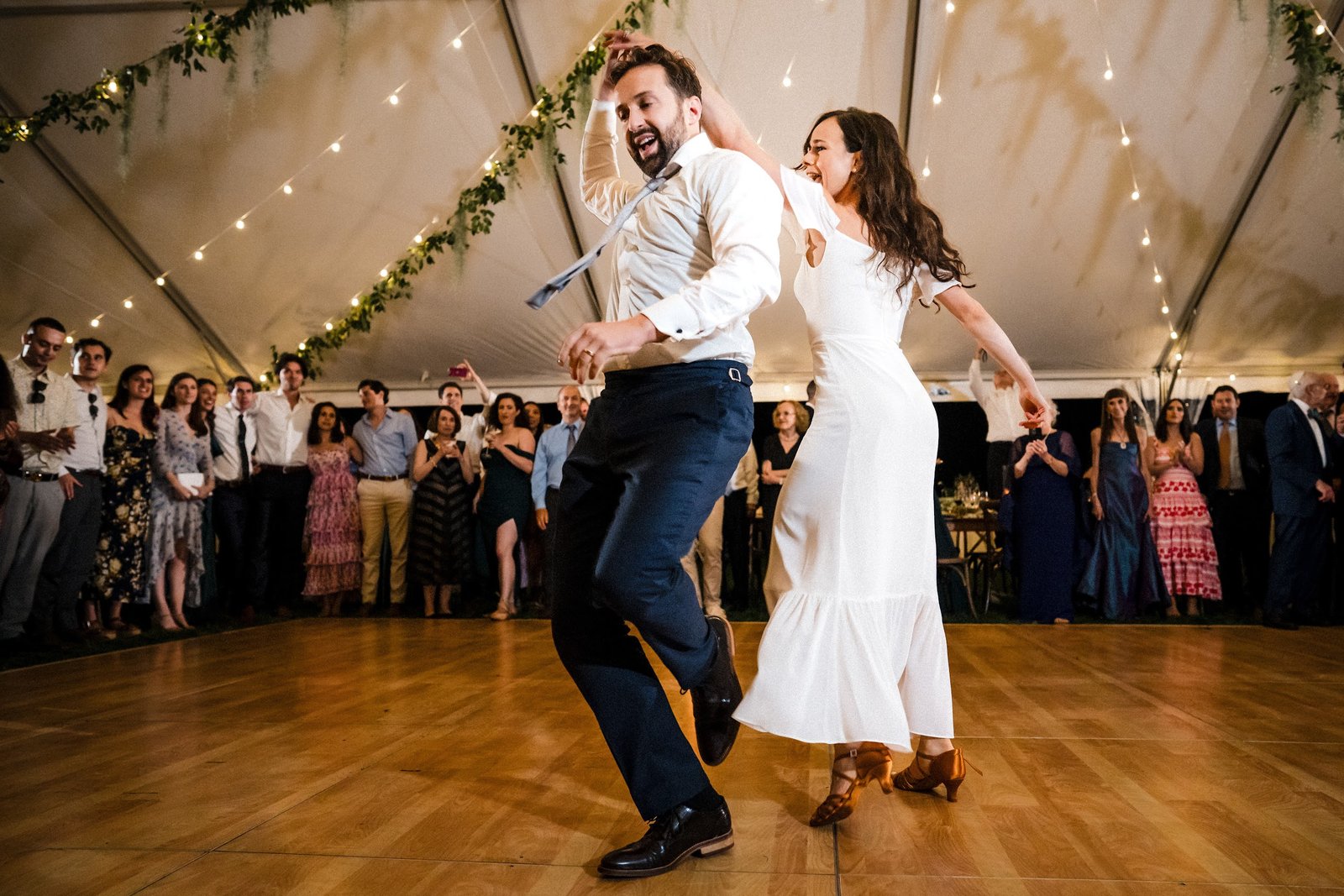 Couple dancing energetically on a wood dance floor at an outdoor tented Salt Lake City reception