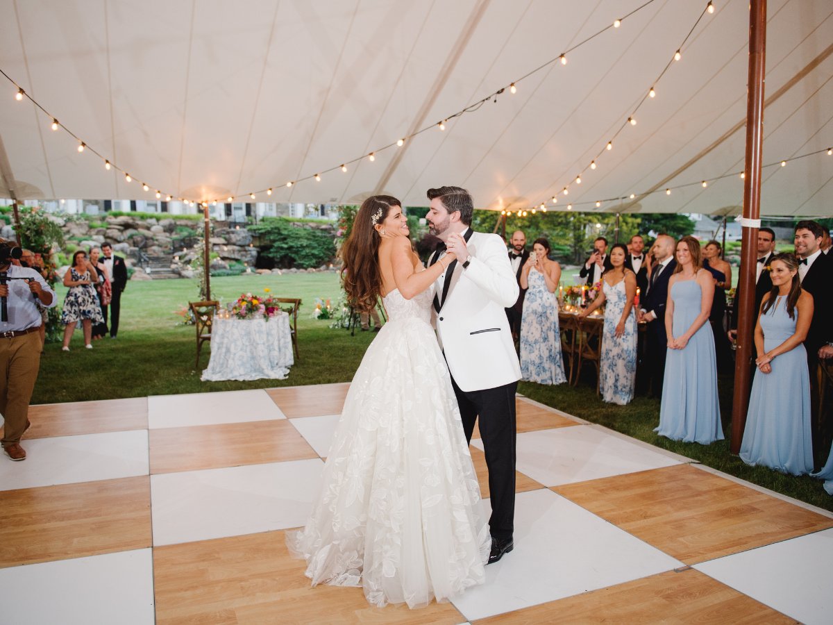 Couple's first dance on a checkerboard patterned dance floor under a tent at a Salt Lake City reception